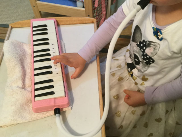 鍵盤ハーモニカを拭いている子供