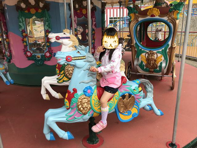 神戸王子動物園遊園地「メリーゴーランド」の馬に乗る娘